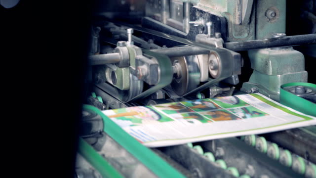 Printed-magazines-are-going-along-the-conveyor-belt-when-mechanical-razors-cut-off-their-extra-sides