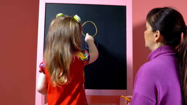 Mother-teaches-her-daughter-to-draw-with-chalk.