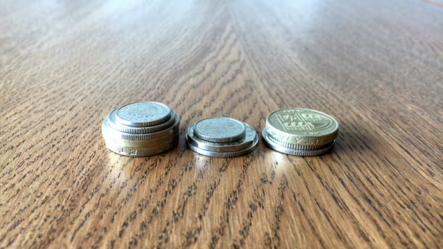 Geld-wächst-Konzept.-Zarte-Frauenhand-legen-Münzen-auf-den-Tisch.-Close-Up