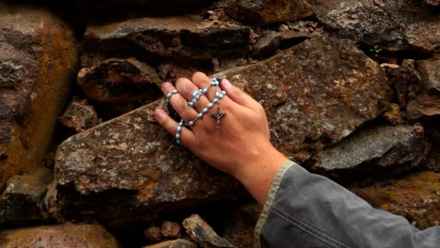 Arm-with-rosary-on-stone-wall