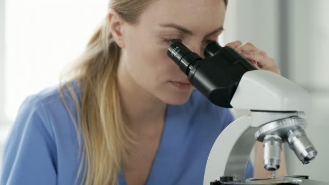 Weibliche-Biochemiker-Mikroskop-bei-der-Arbeit