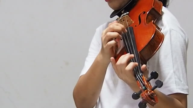 the-lady-is-showing-method-of-playing-by-plucking-the-strings-with-the-finger,the-Pizzicato-technique-of-violinist.