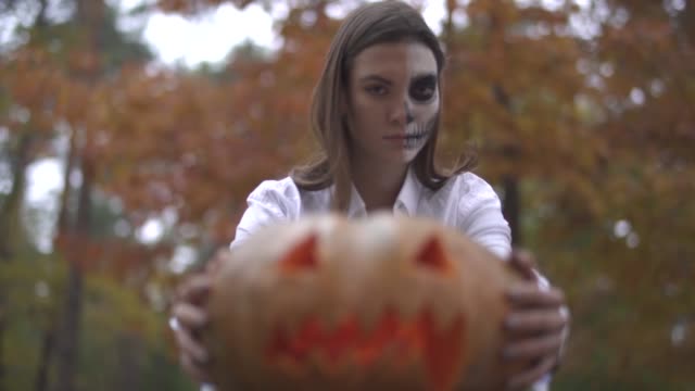 Halloween.-Woman-with-a-scary-Halloween-makeup-holding-a-pumpkin-in-his-hands