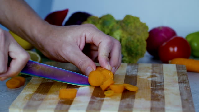 Man-is-cutting-vegetables-in-the-kitchen,-slicing-carrot