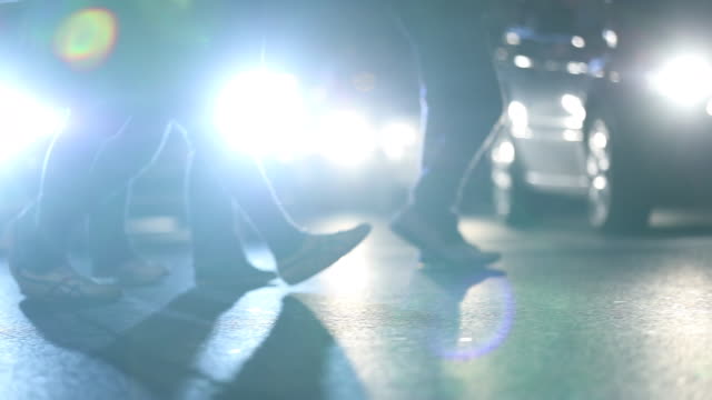 Pedestrians-feet-crossing-street-at-night-with-lens-flares-hitting-camer-ain-the-background