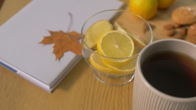 Buch,-Zitrone,-Tasse-Tee,-Nüsse-und-Gebäck-auf-Tisch