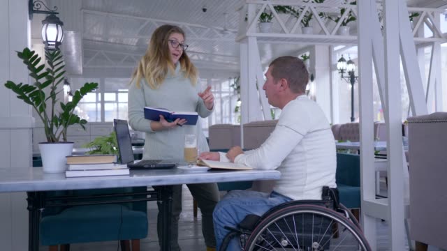 Training-für-ungültig,-glückliche-kranke-Schüler-reife-Männer-im-Rollstuhl-mit-Erzieher-weibliche-verwenden-intelligente-Computertechnik-bei-persönlichen-Vortrag