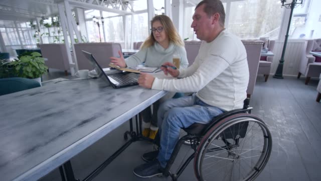freelance-businessman-is-disabled-on-wheelchair-with-woman-using-smart-computer-technology-for-developing-and-planning-business-ideas