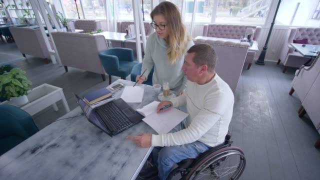 professional-training-of-invalid-senior-men-in-wheelchair-with-teacher-woman-using-laptop-computer-during-individual-teaching