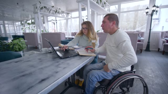 Kurse-für-Behinderte,-Smart-schmerzenden-Student-Reifen-Männer-im-Rollstuhl-mit-Tutor-Weibchen-während-schulfreie-Bildung-mit-Hilfe-moderner-Computertechnik