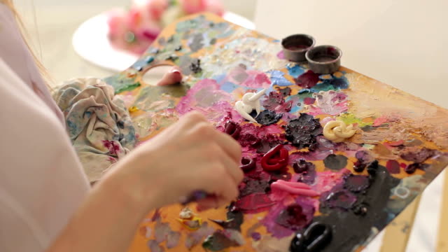 El-artista-mezcla-pinturas-al-óleo-en-una-paleta-con-un-cepillo,-Close-up.