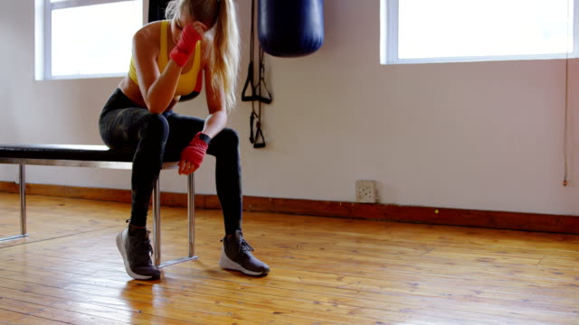 Female-boxer-relaxing-in-fitness-studio-4k