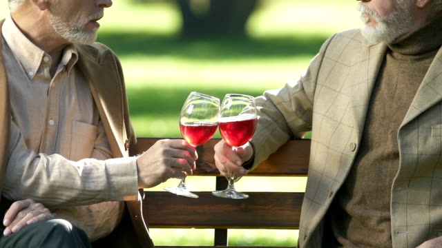 Aged-gentlemen-drinking-wine,-enjoying-alcohol-beverage-taste,-relax-outside
