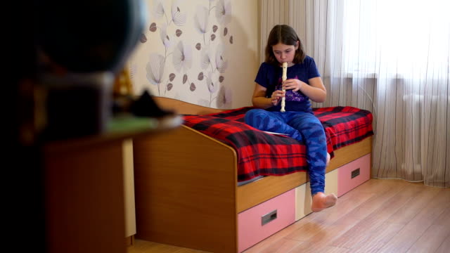 Mädchen-Flötenspiel-auf-ihrem-Bett
