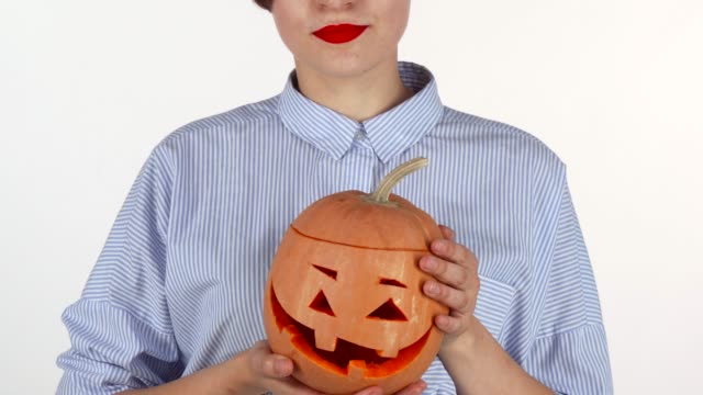 Frau-trägt-roten-Lippenstift-hält-geschnitzten-Halloween-Kürbis