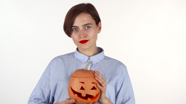 Beautiful-woman-with-red-lips-smiling-happily,-holding-Halloween-pumpkin