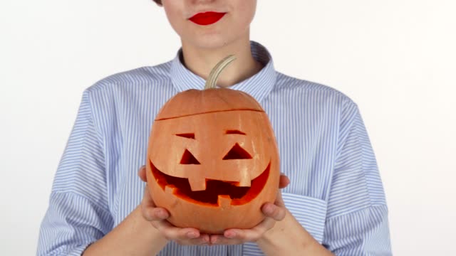 Red-lipped-woman-holding-out-carved-Halloween-pumpkin-to-the-camera