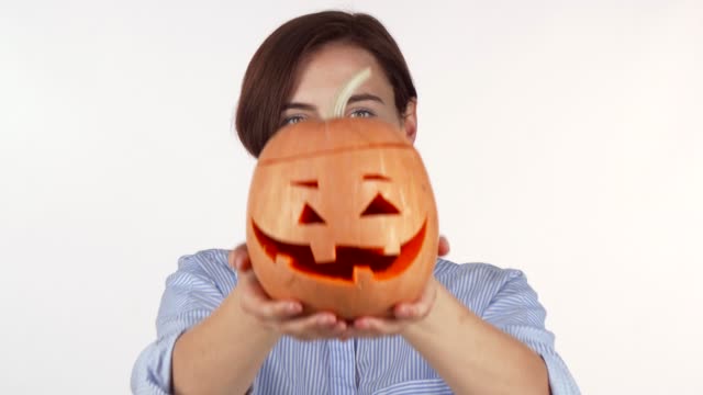 Frau-versteckt-ihr-Gesicht-hinter-geschnitzten-Halloween-Kürbis