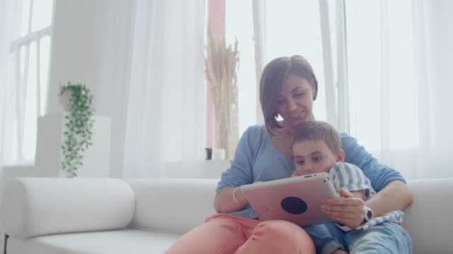 Madre-e-hijo-jugando-con-la-tableta-digital-en-casa.-Joven-madre-con-sus-5-años-sonriendo-con-tableta-digital-en-casa.