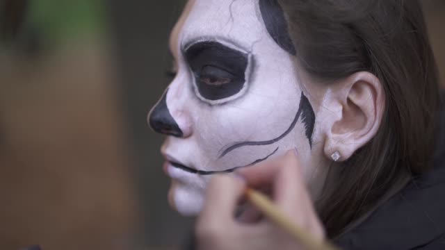 Halloween.-Make-up-Künstler-wendet-Make-up-auf-Mädchen-Gesicht