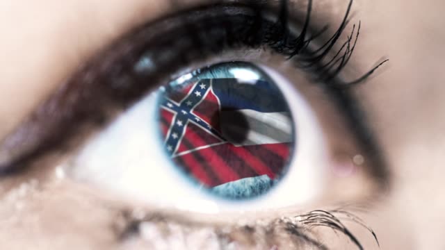 Woman-blue-eye-in-close-up-with-the-flag-of-Mississippi-state-in-iris,-united-states-of-america-with-wind-motion.-video-concept