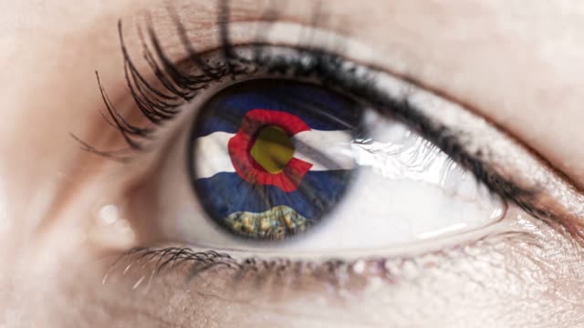 Frau-grünes-Auge-in-Nahaufnahme-mit-der-Flagge-von-Colorado-Staat-in-Iris,-vereinigte-Staaten-von-Amerika-mit-Windbewegung.-Videokonzept