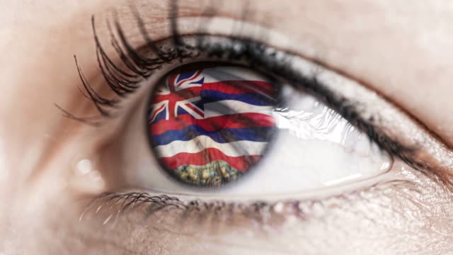 Woman-green-eye-in-close-up-with-the-flag-of-Hawaï-state-in-iris,-united-states-of-america-with-wind-motion.-video-concept
