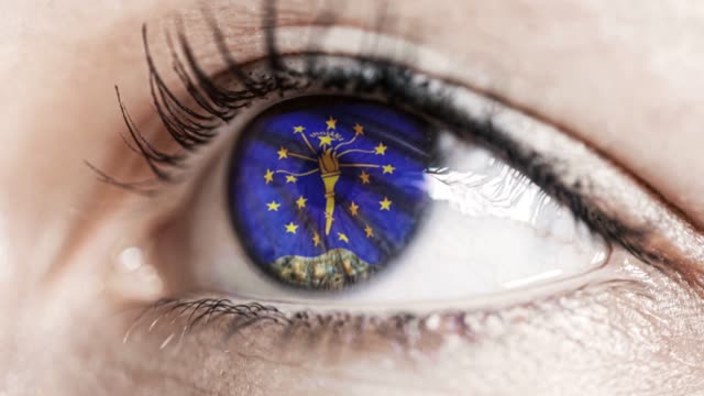 Woman-green-eye-in-close-up-with-the-flag-of-Indiana-state-in-iris,-united-states-of-america-with-wind-motion.-video-concept