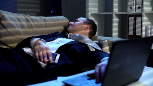 Tired-businessman-is-sleeping-on-the-sofa-at-the-office