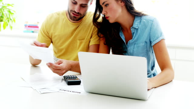 Worried-couple-calculating-their-bills-with-laptop-in-the-kitchen