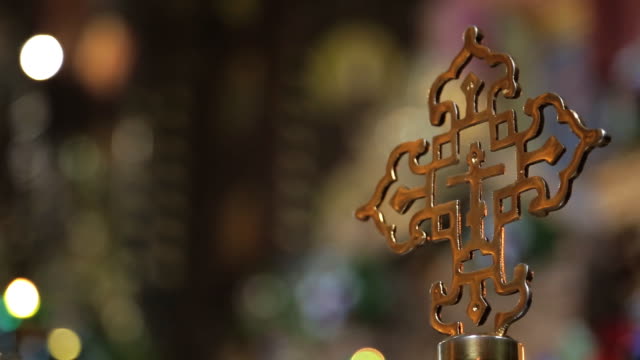 Golden-religious-cross-on-background-of-the-lights-in-church