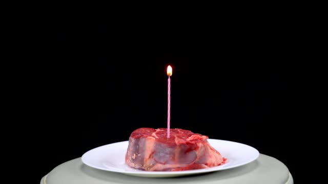 Ein-Stück-Rindfleisch-mit-einer-brennenden-Kerze-in-der-Mitte-auf-einem-schwarzen-Hintergrund