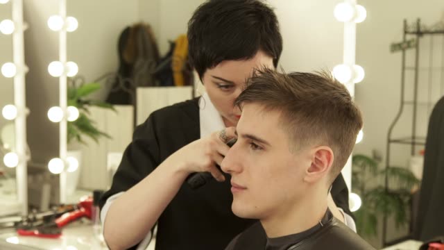 Barber-making-male-haircut-with-electric-shaver-in-barber-shop.-Close-up-hairdresser-cutting-hair-with-hair-machine-in-beauty-studio.-Man-hairdressing-with-electric-razor