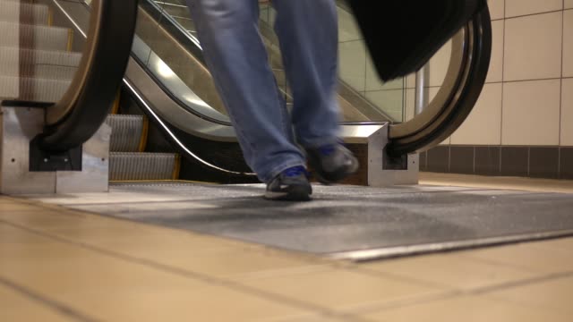 Man-steps-of-an-escalator-onto-the-floor-below