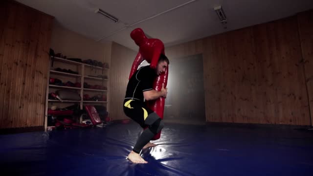 Junger-Mann-schlagen-dummy-Boxsack-im-Fitness-Studio-während-des-Übens-Kampftechnik