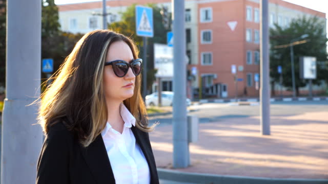 Profile-of-young-businesswoman-walking-along-urban-street-at-sunset-time.-Business-woman-going-to-work.-Confident-girl-being-on-his-way-to-office.-Sun-flare-at-background.-Slow-motion-Close-up