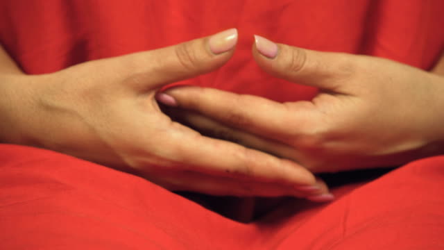 Weiblichen-buddhistischen-in-bunten-roten-Gewand-bereitet-sich-auf-Meditation,-Hände-gekreuzt