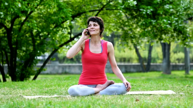 Chica-está-hablando-en-un-teléfono-móvil-durante-yoga-ejercicio-entrenamiento