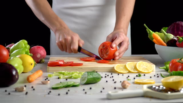Chef-is-cutting-vegetables-in-the-kitchen,-slicing-tomato