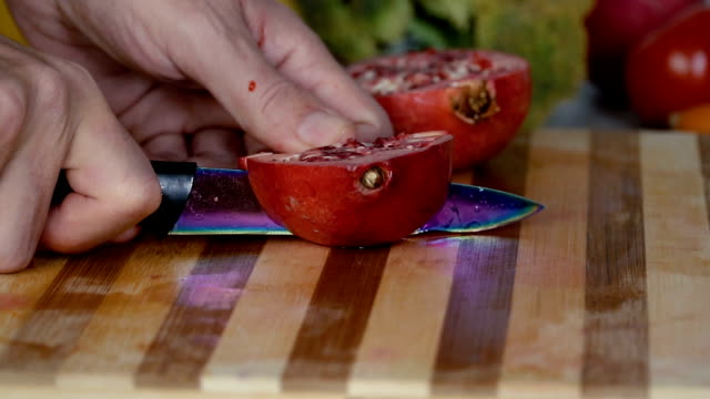 Man-is-cutting-pomegranate-on-cutting-board