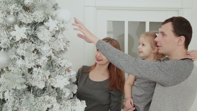 La-familia-está-de-pie-cerca-del-árbol-de-Navidad,-reir-hablar-y-tocar-juguetes-esperando-Navidad