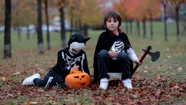 Niños-divirtiéndose-con-halloween-tallado-de-calabaza-en-un-parque,-vistiendo-trajes-de-miedo-y-jugando-con-juguetes