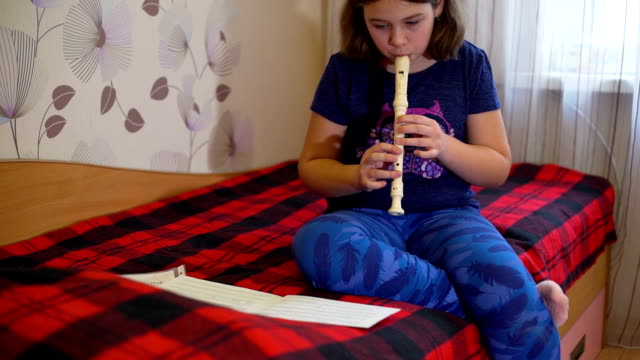 Mädchen-auf-dem-Bett-sitzt-und-Flötenspiel