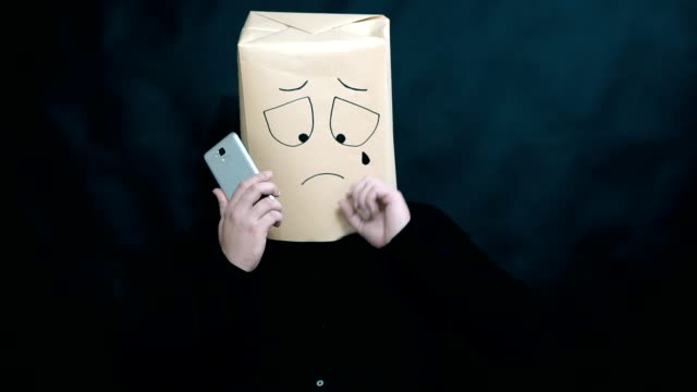 The-concept-of-emotions.-A-man-listens-to-a-message-on-a-smartphone.-He-wipes-tears-on-his-face.-Facial-expression-of-despondency-and-extreme-disappointment.-A-tear-drips.