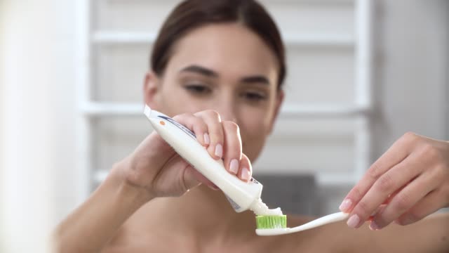 Zähne-Hygiene.-Frau-Anwendung-Zahnpasta-auf-die-Zahnbürste-Closeup