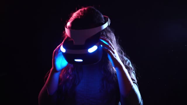 Mujer-joven-en-VR-auriculares-de-pie-en-el-espacio-oscuro