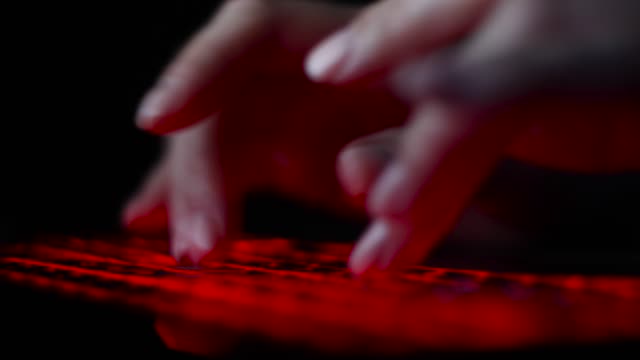 Hacker-Mädchen-Hand-tippen-auf-Tastatur-mit-roter-Hintergrundbeleuchtung