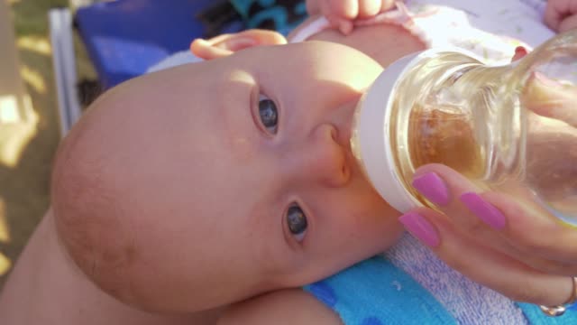 Baby-liegt-auf-dem-Schoß-der-Mütter-und-trinkt-aus-der-Flasche