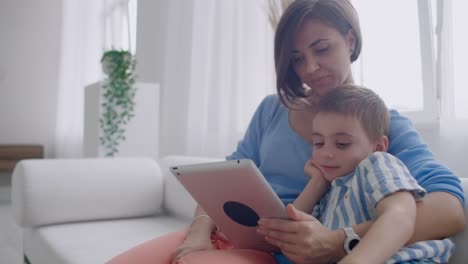 Madre-e-hijo-jugando-con-la-tableta-digital-en-casa.-Joven-madre-con-sus-5-años-sonriendo-con-tableta-digital-en-casa.