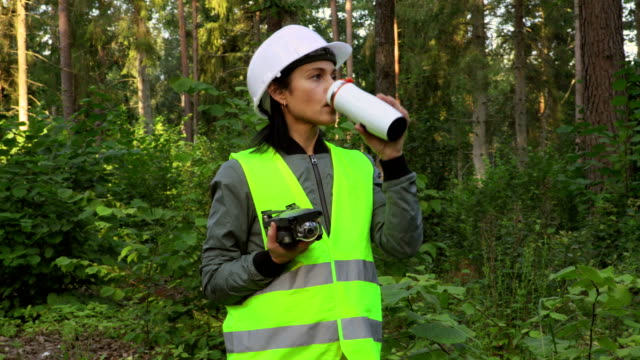 Woman-holding-Drone-quadcopter-and-drinking-coffee-before-forest-inspection